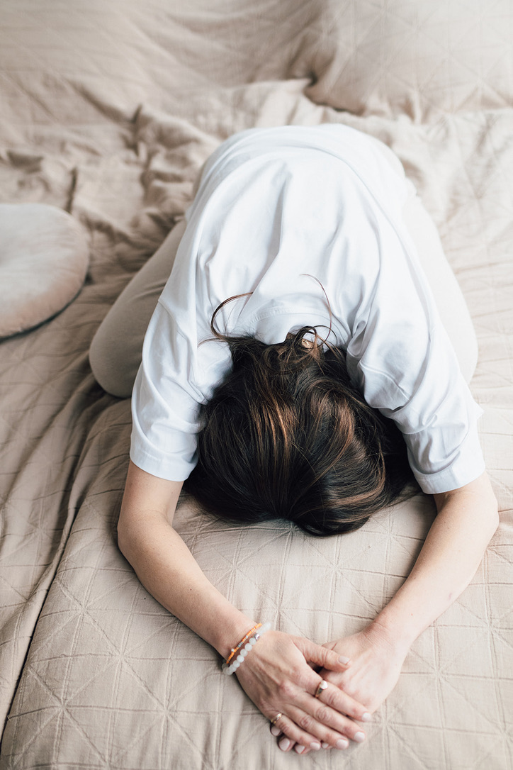 Christiane liegt in einer weiten Vorbeuge auf dem Bett und spürt in die Bewegung hinein